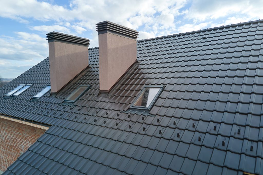 jng services Closeup of attic fixed skylight windows and brick chimneys on house roof top covered with ceramic shingles. Tiled covering of building.