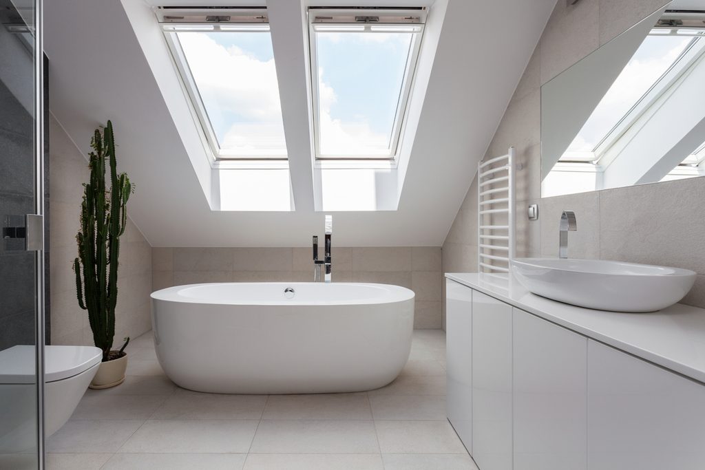 Porcelain freestanding bath in designed white bathroom with velux skylight by JNG Services